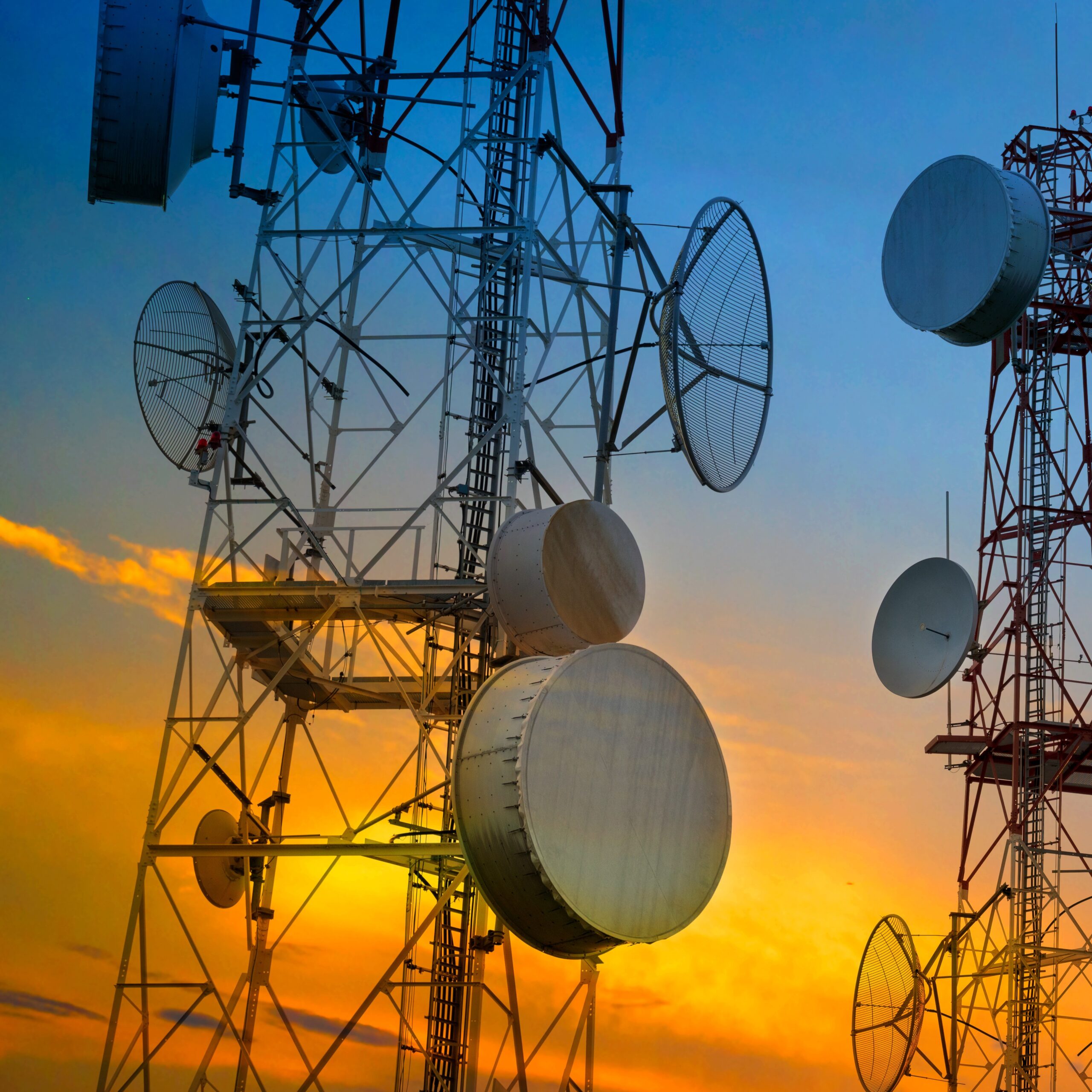 Telecommunication towers with wireless antennas on sunset sky